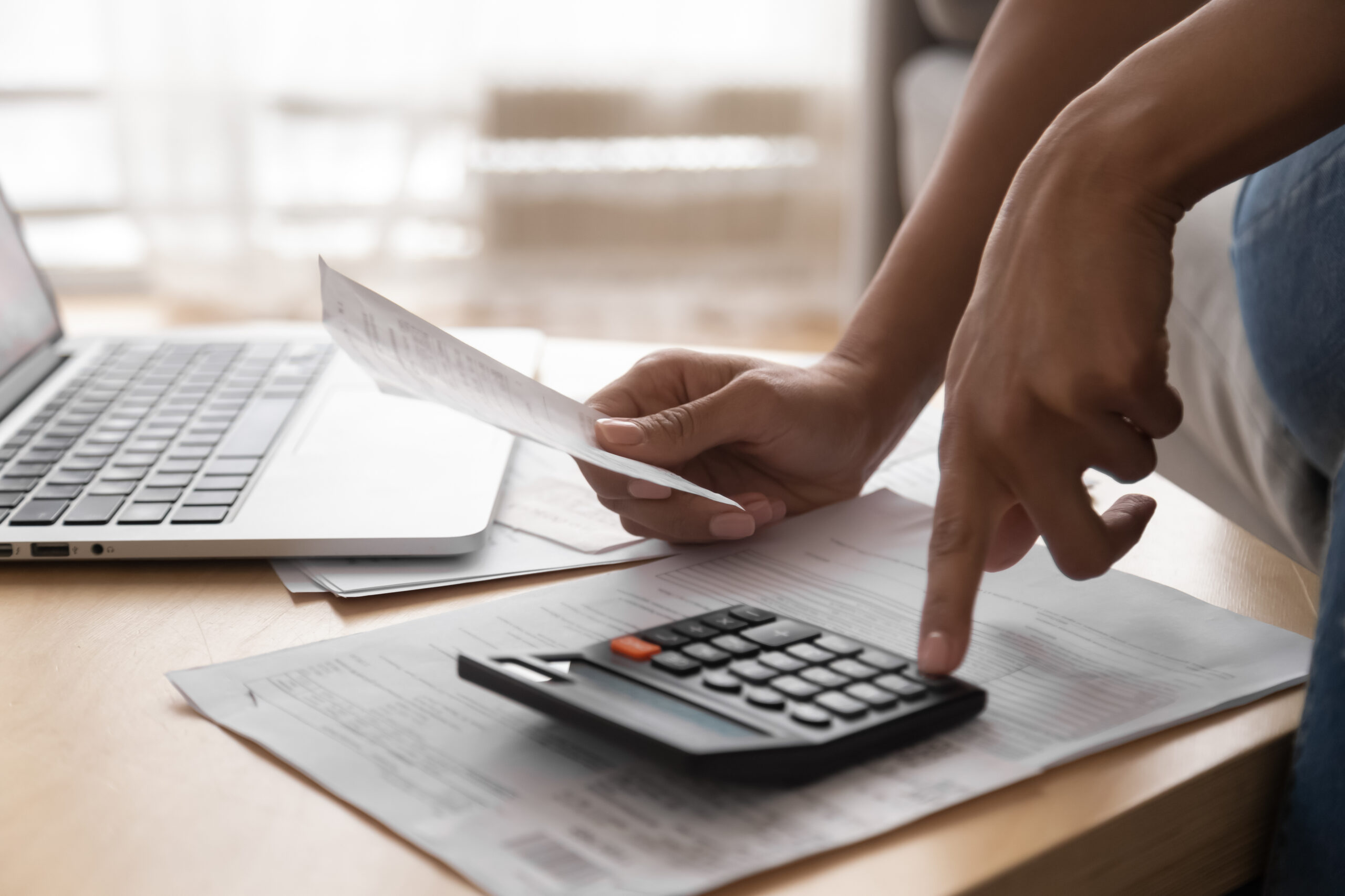 African woman holding paper bills using calculator